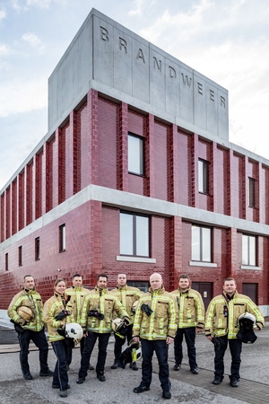 8 brandweerlieden in interventiekledij voor de brandweerkazerne. 8 brandweerlieden in interventiekledij voor de brandweerkazerne.