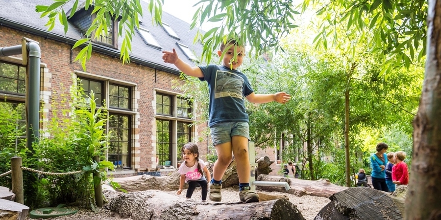 Een jongetje loopt over een boomstam op een klimaatrobuuste natuurspeelplaats Een jongetje loopt over een boomstam op een klimaatrobuuste natuurspeelplaats