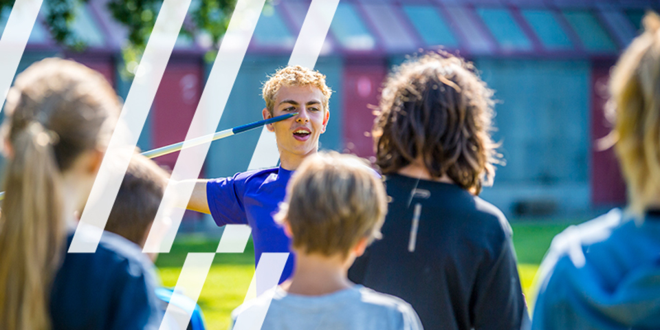 Lesgever legt uit hoe je moet speerwerpen aan een groep kinderen