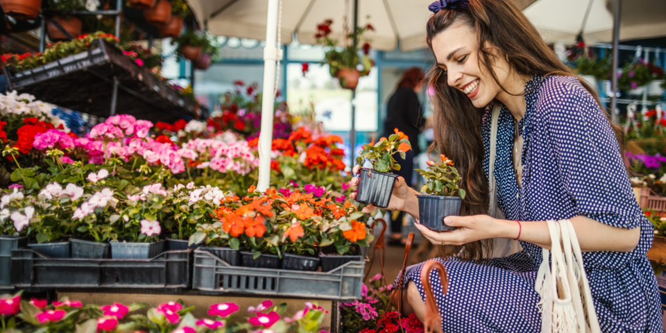 Vrouw koopt planten op lentemarkt.