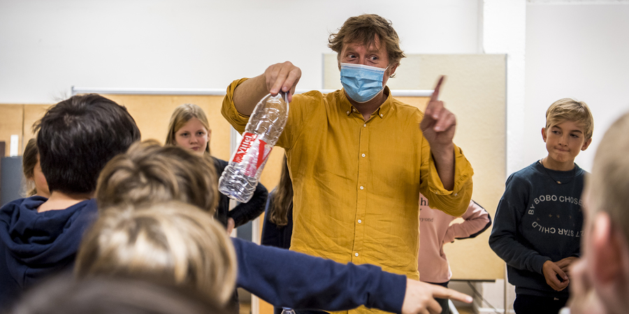 een begeleider met mondmasker geeft les aan kinderen een begeleider met mondmasker geeft les aan kinderen