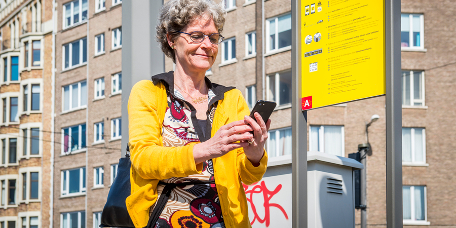 Een vrouw kijkt op haar smartphone terwijl ze naast een taxistand staat. Een vrouw kijkt op haar smartphone terwijl ze naast een taxistand staat.