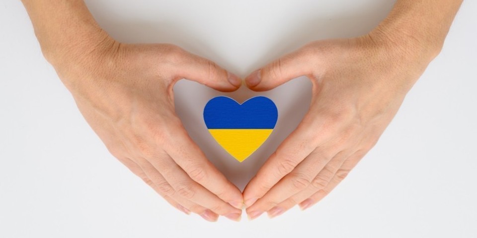 Twee handen vouwen zich samen in de vorm van een hart met daarin een vorm in geel-blauwe kleuren