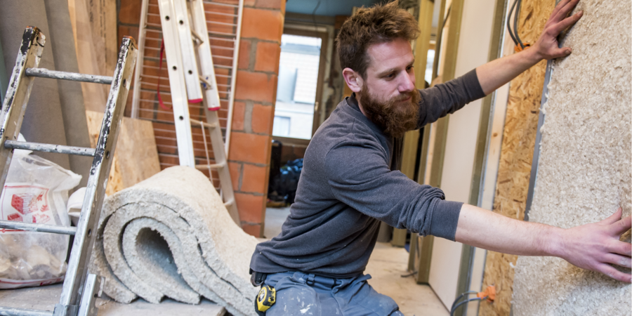 Een man op een bouwwerf plaatst nieuwe isolatie in de muur. Een man op een bouwwerf plaatst nieuwe isolatie in de muur.