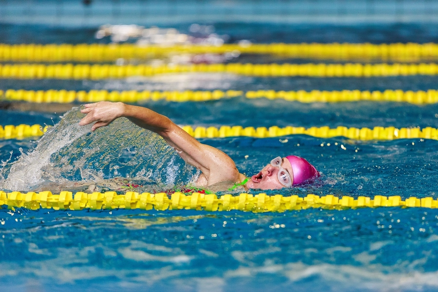 Een vrouw met roze badmuts zwemt haar baantjes