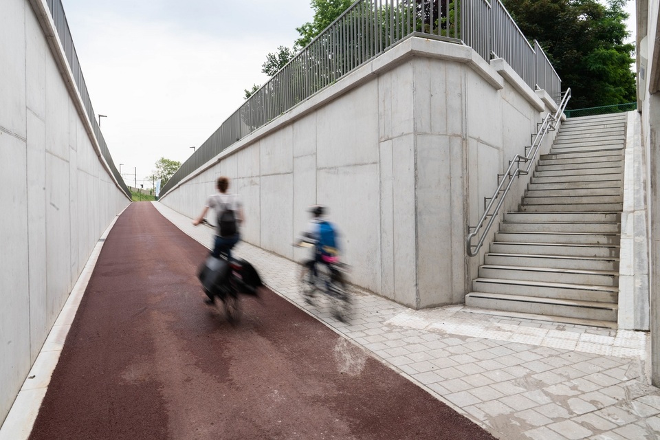 Een volwassene en een kind fietsen door de fietstunnel